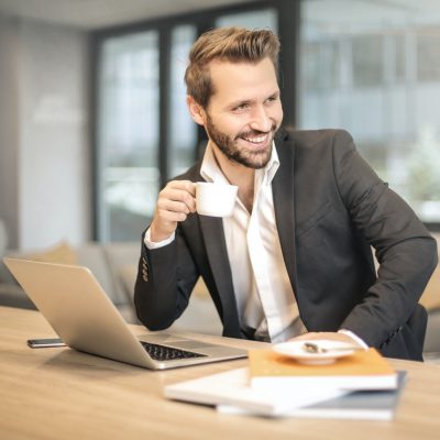 man met laptop en koffie aan het werk